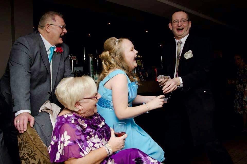 Group of four people laughing and enjoying a celebration in a dimly lit room.